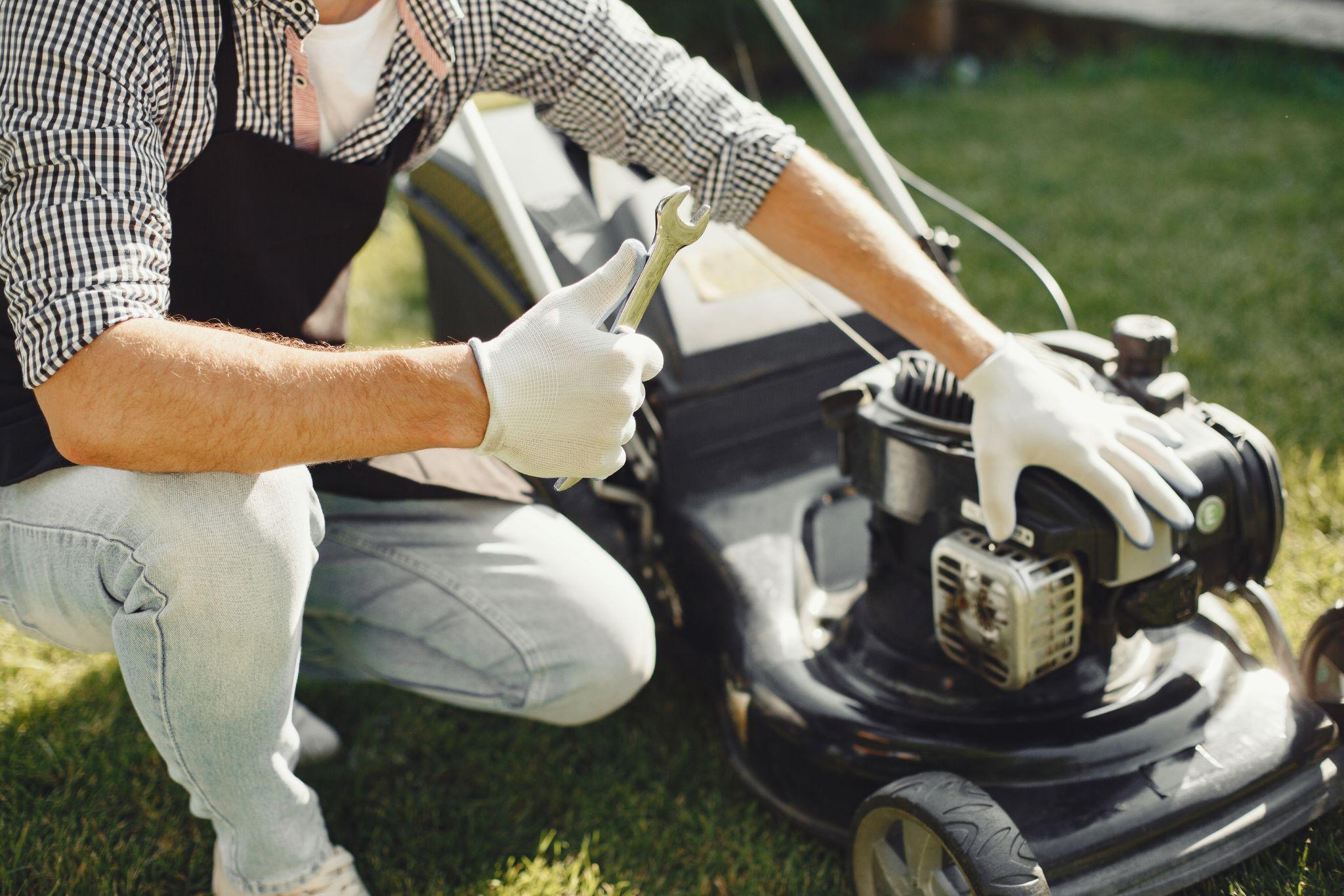 Man in gloves repairing a black lawn mower