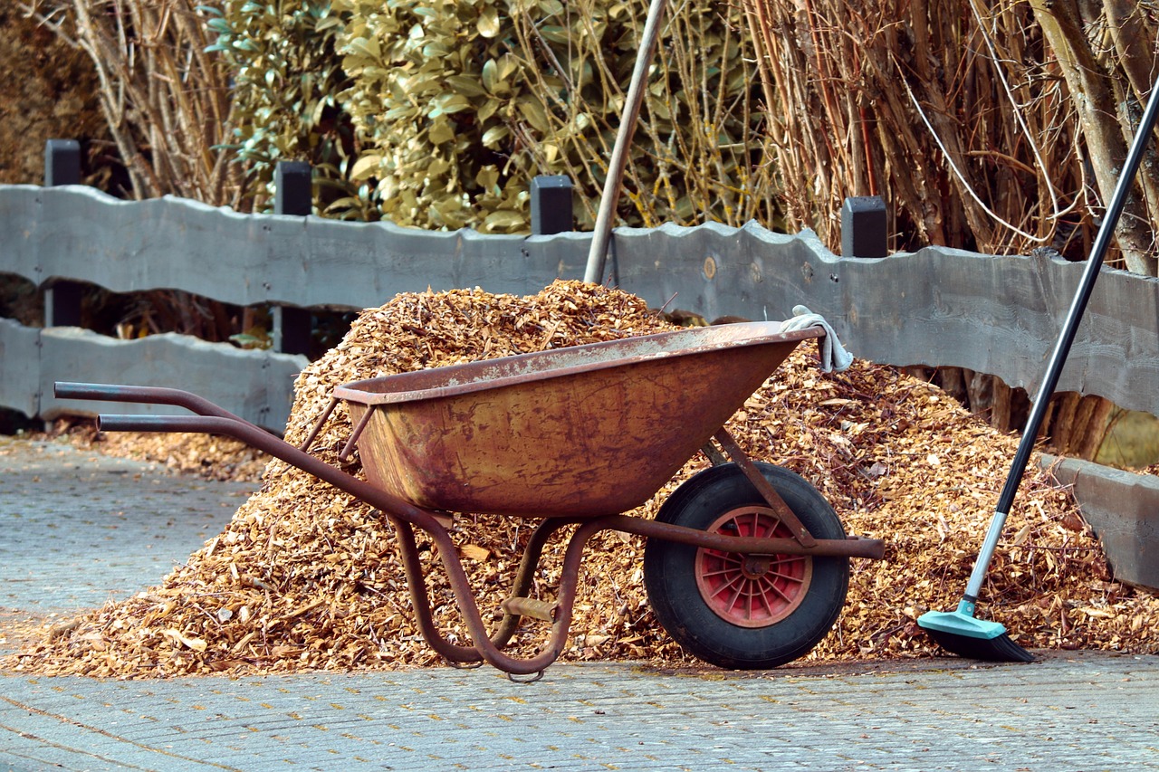 a pile of mulch on a street with a wheelbarrow and broom