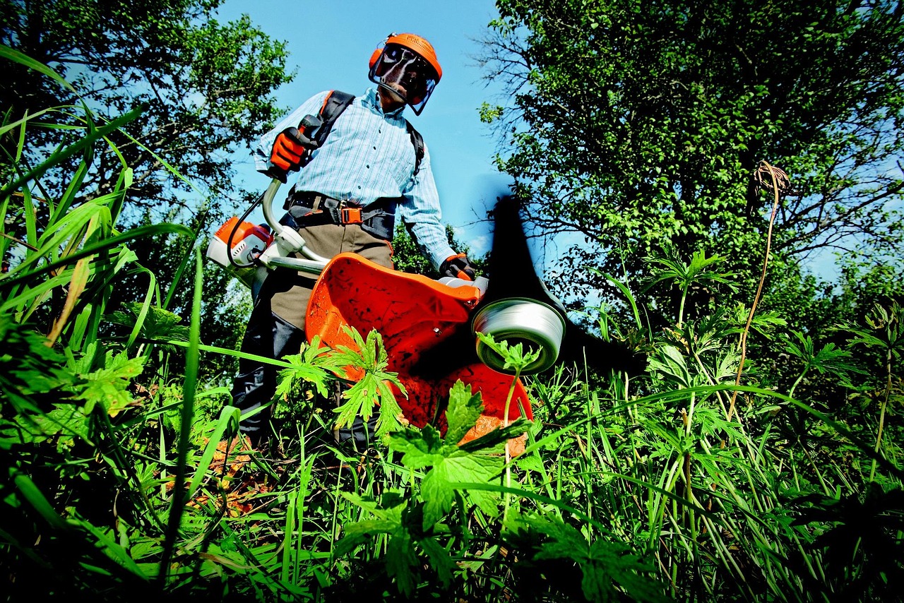 a person wearing a red helmet cutting grass