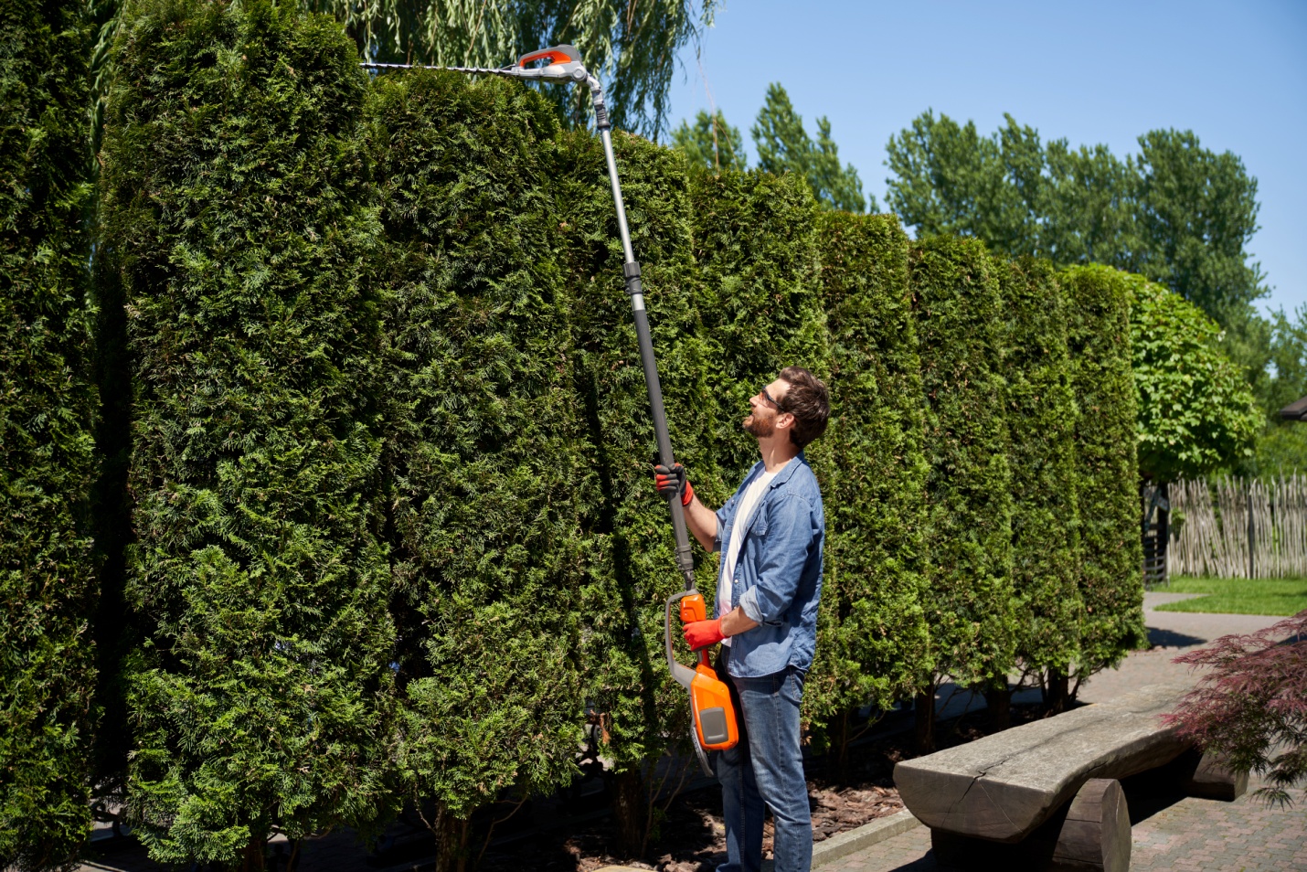 a person using a machine to trim hedges